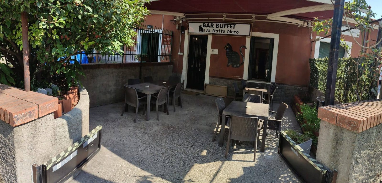 L'ingresso del Bar Buffet al Gatto Nero in Strada della Rosandra 60 a Trieste, con l'insegna e i tavoli all'aperto